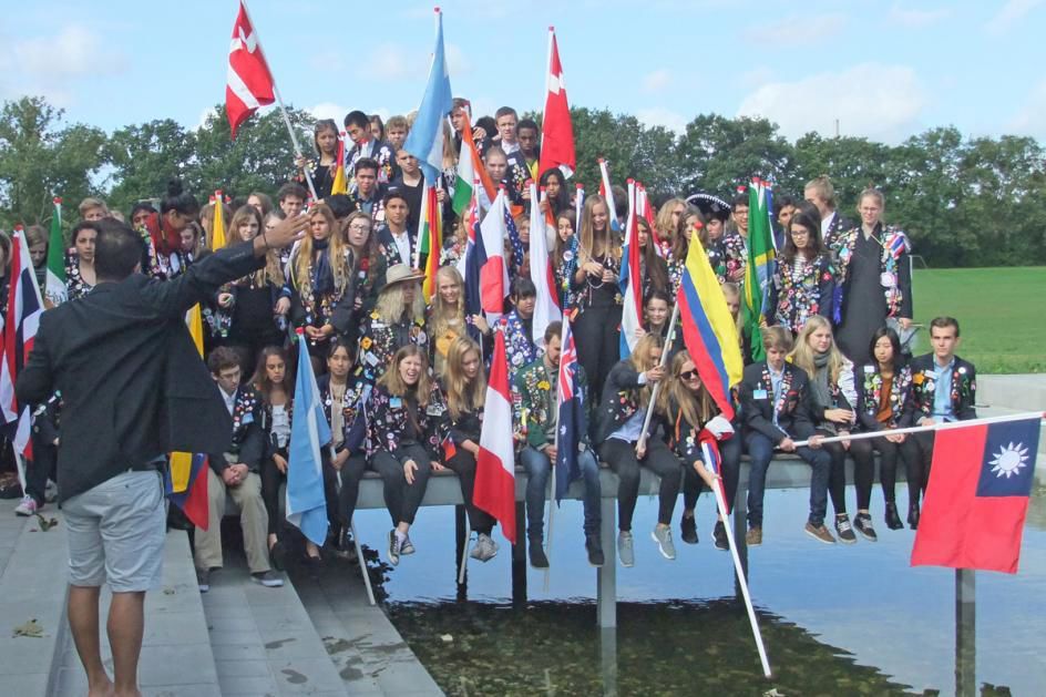 En gruppe unge sidder på en badebro. De holder en masse flag fra forskellige lande.